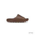 ADIDAS YEEZY SLIDE FLAX in brown, featuring a smooth upper and a ridged, wavy sole.