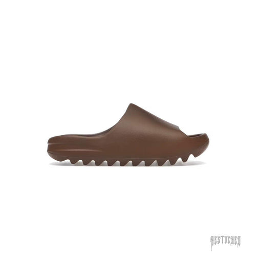 ADIDAS YEEZY SLIDE FLAX in brown, featuring a smooth upper and a ridged, wavy sole.