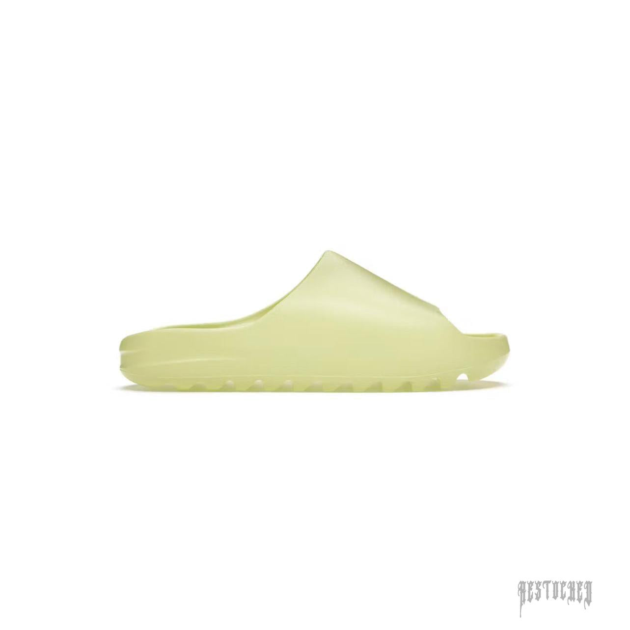 ADIDAS YEEZY SLIDE GLOW GREEN, a single, light green foam slide with a thick sole and ridged tread.