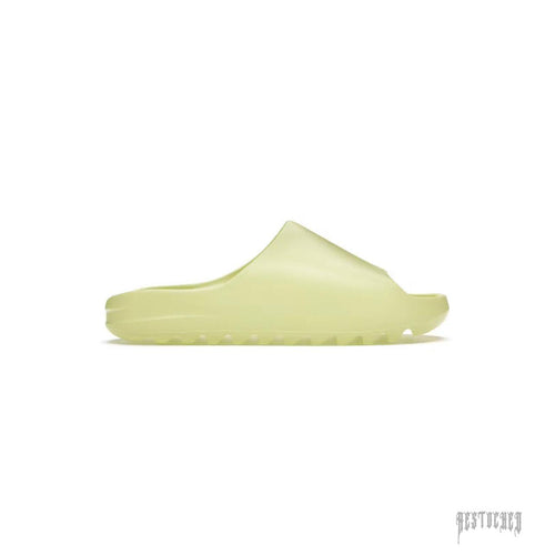 ADIDAS YEEZY SLIDE GLOW GREEN, a single, light green foam slide with a thick sole and ridged tread.