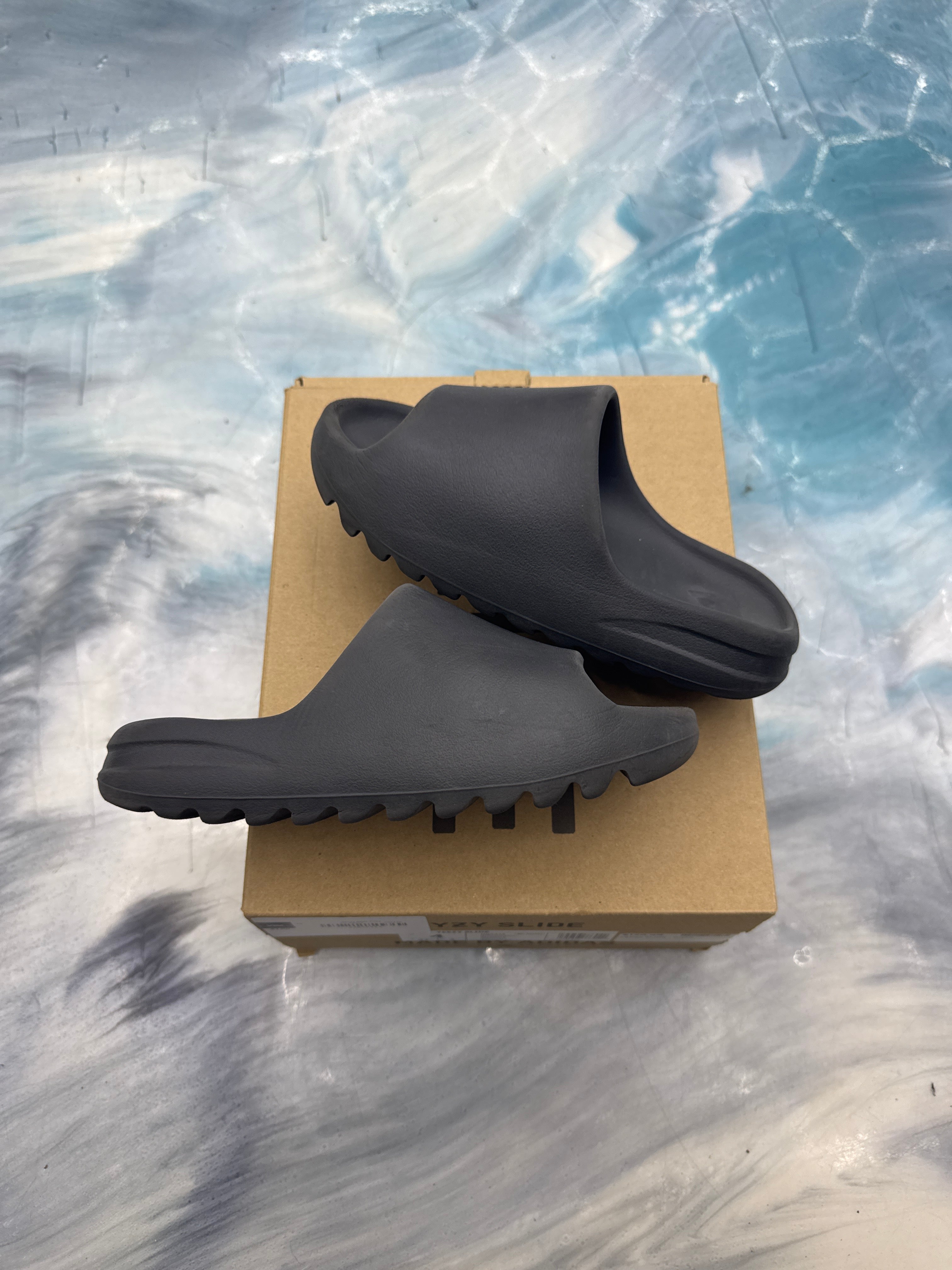 ADIDAS YEEZY SLIDE ONYX PRE OWNED SIZE 4, dark gray foam slides with ridged soles on a brown box.