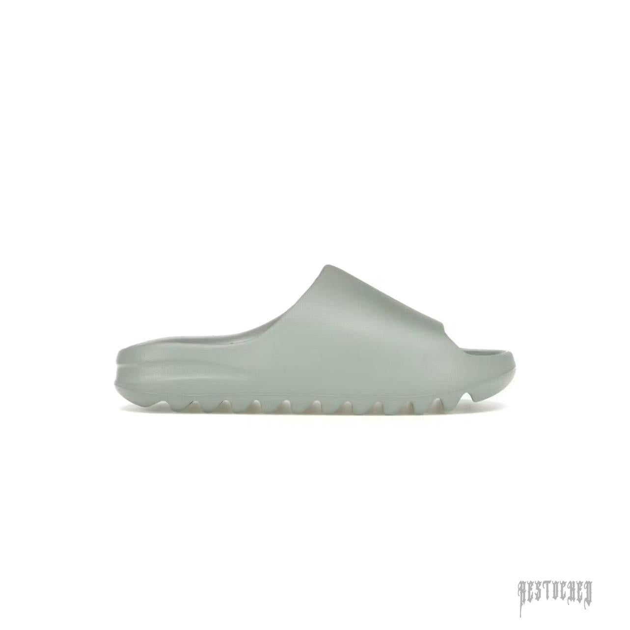 Adidas Yeezy Slide "Salt" in a minimalist light grey-green foam design with a ridged sole.