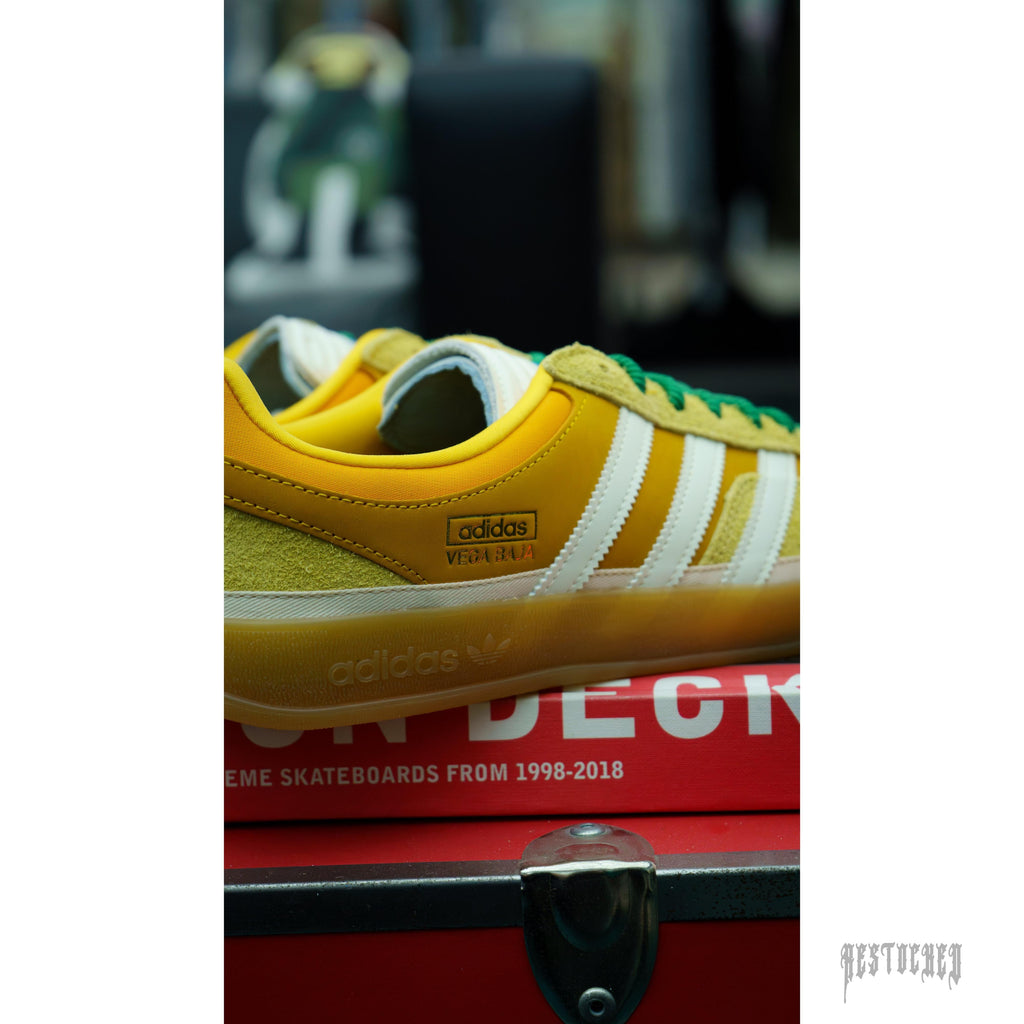 Bad Bunny Adidas Gazelle Indoor Vega Baja sneakers: yellow suede and leather, white stripes, green laces, gum sole.