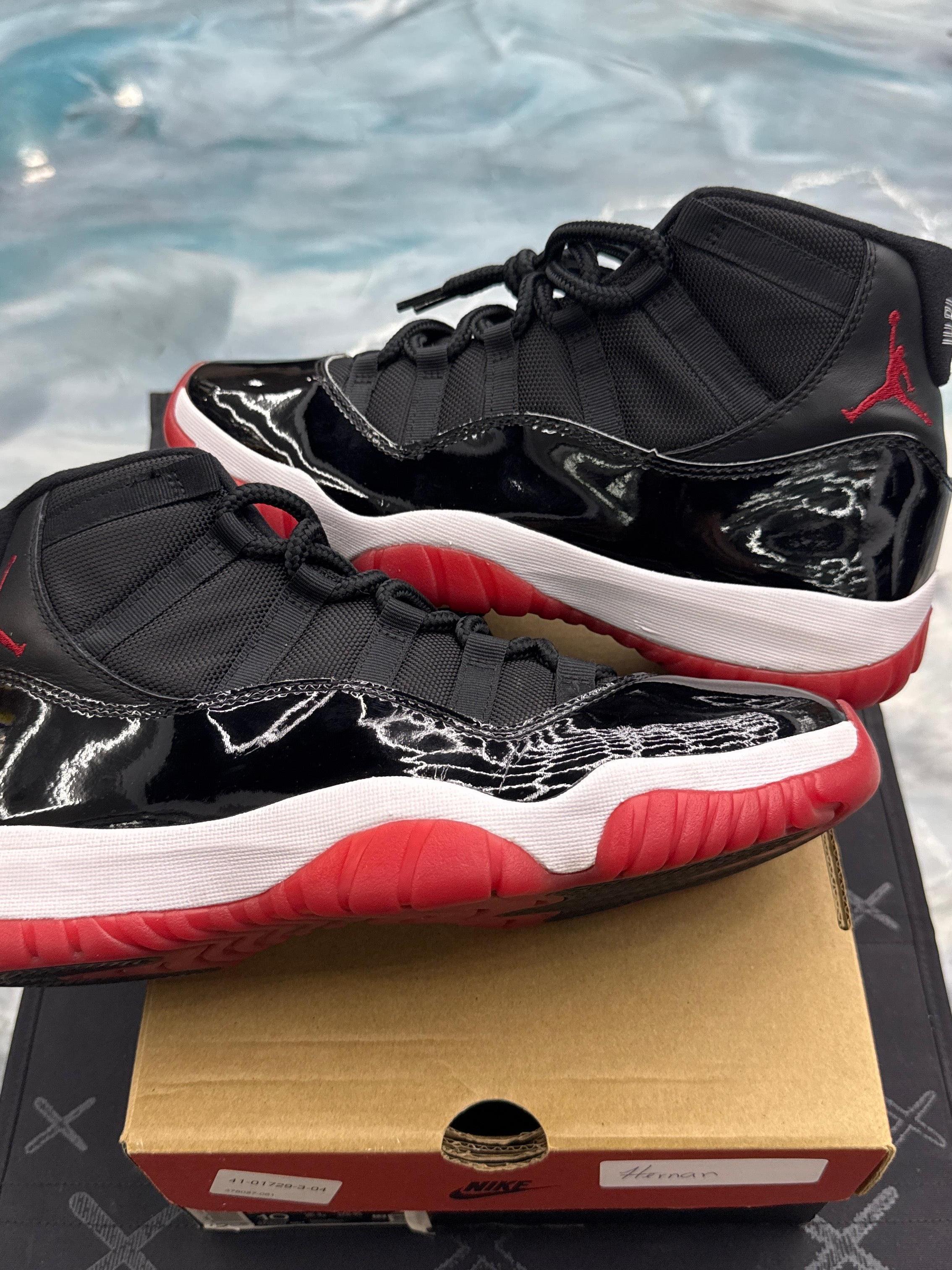 Pre-owned Jordan 11 Retro Playoff Bred sneakers, size 10, featuring black patent leather, red soles, and white midsoles.