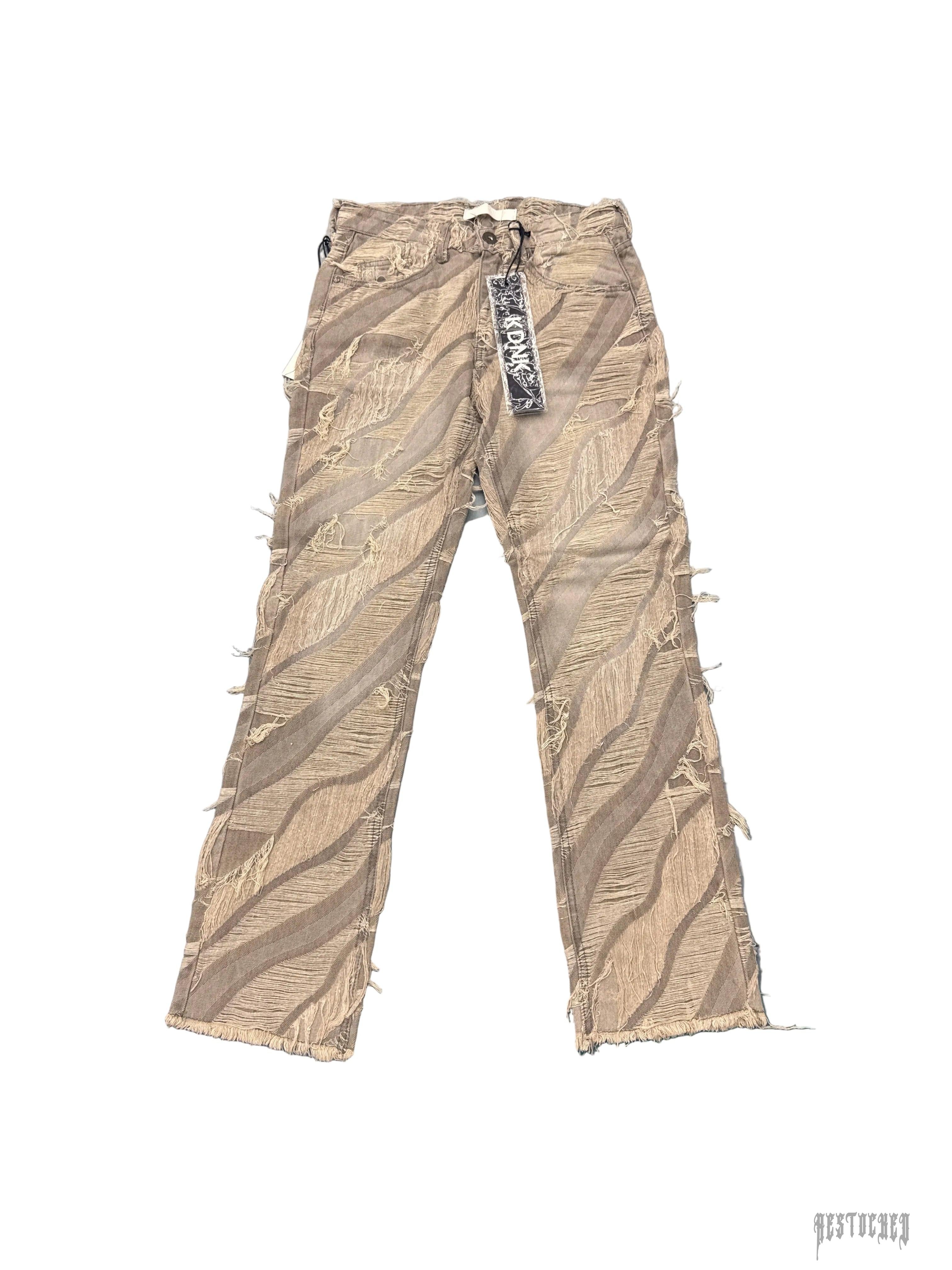KDNK KND4704 distressed beige denim jeans with ripped diagonal stripes and frayed hems.