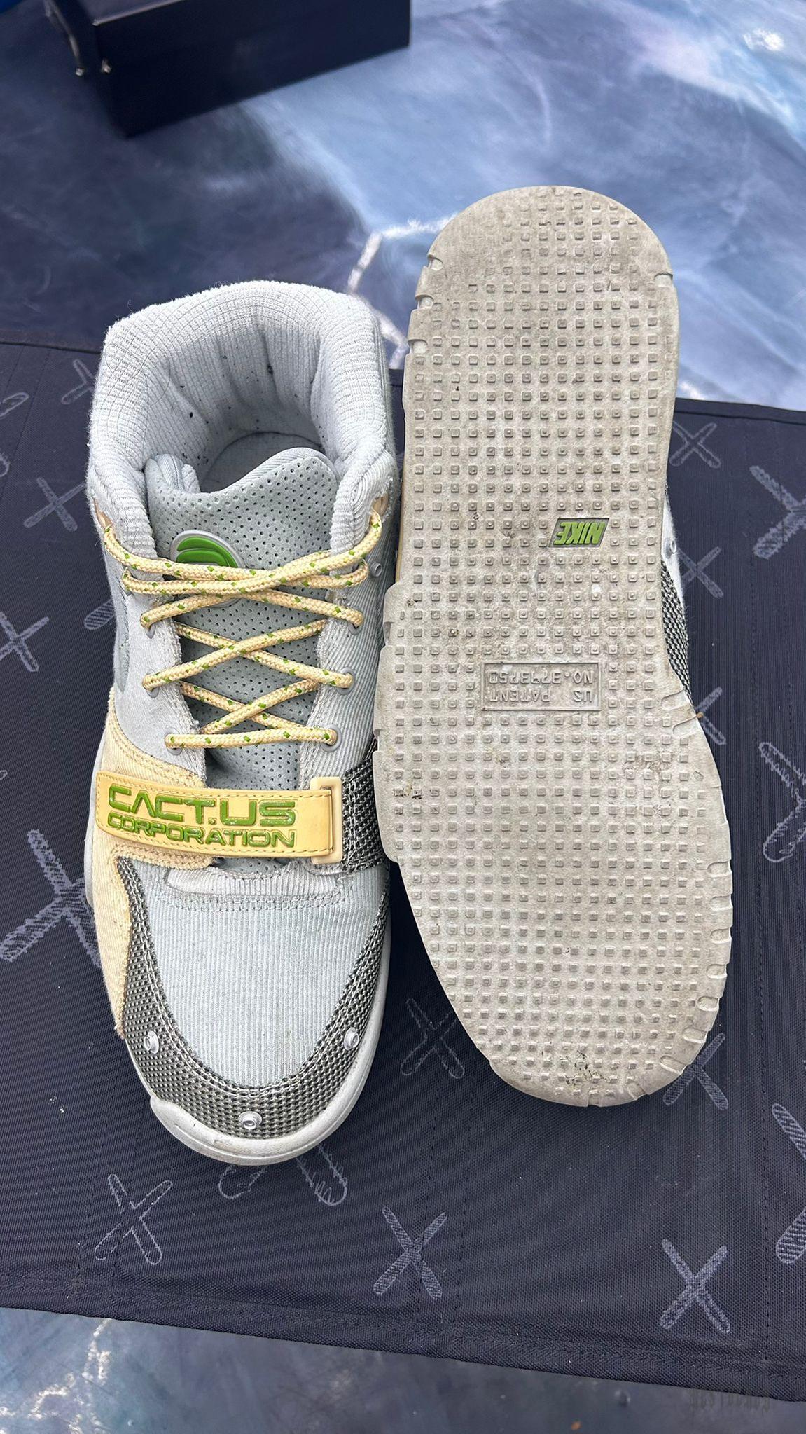 Pre-owned Nike Air Trainer 1 SP Travis Scott Grey Haze size 9.5, top-down view showing grey suede, yellow laces, and "CACT.US CORPORATION" strap.