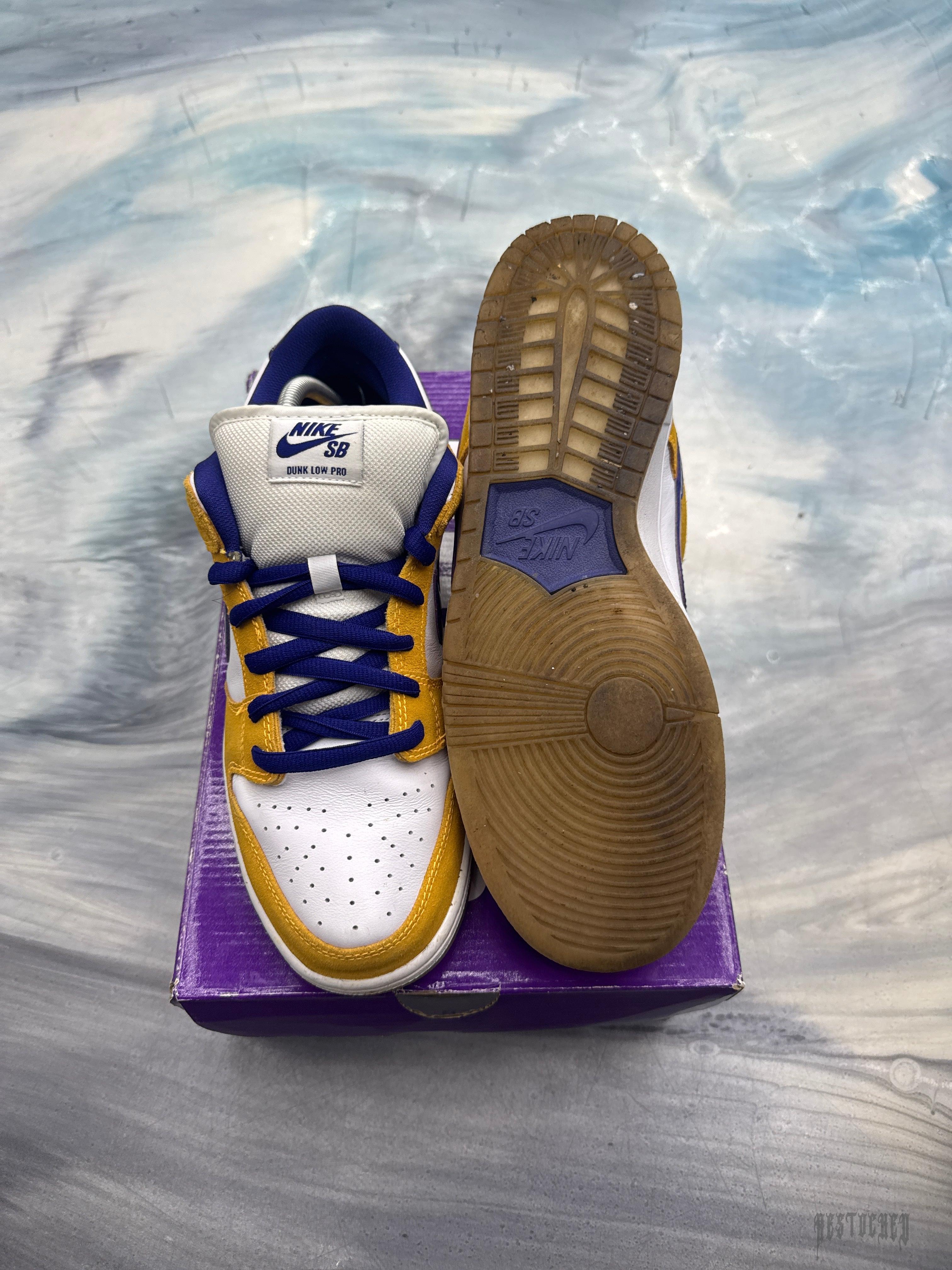 Pre-owned NIKE SB DUNK LOW in Laser Orange and white with blue laces, size 10.5, on a purple box.