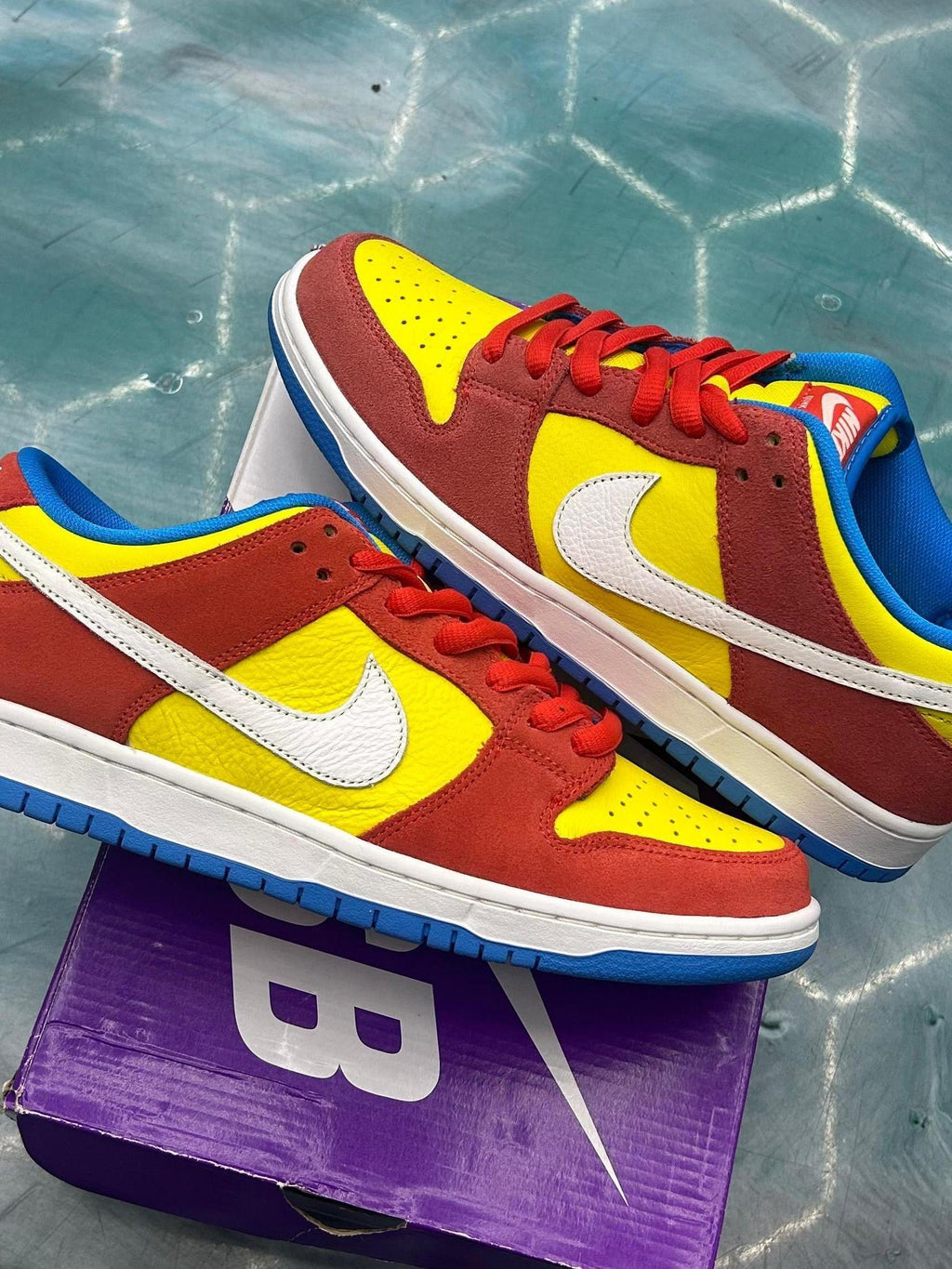 NIKE SB Dunk Low Pro Bart Simpson sneakers, size 10, in yellow, red, blue, and white.