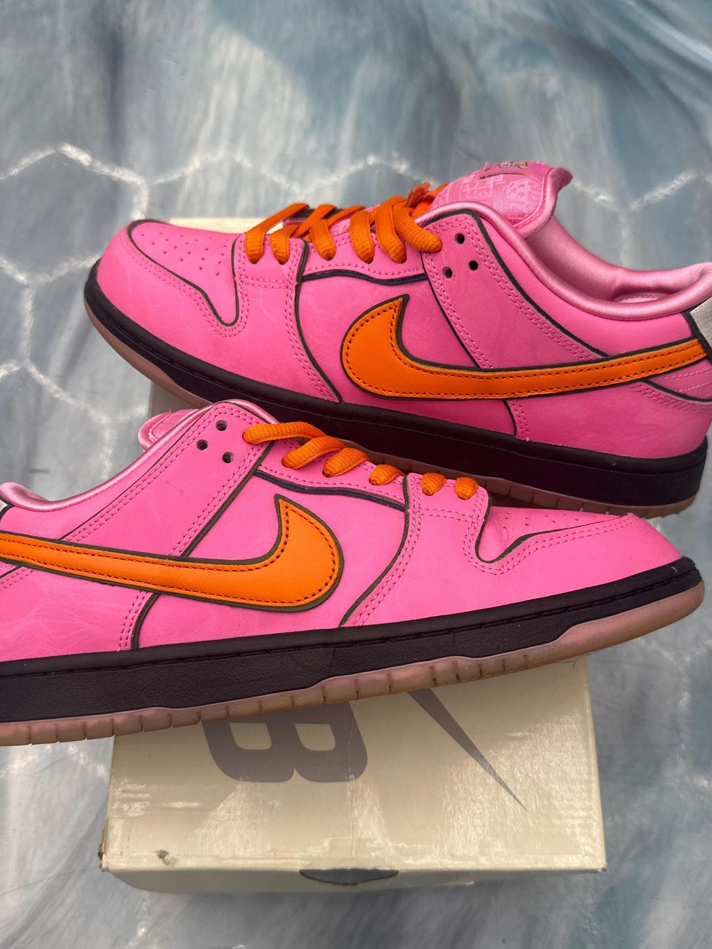 Pink leather Nike SB Dunk Low "Blossom" sneakers with orange swoosh, laces, and black sole.