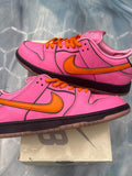 Pink leather Nike SB Dunk Low "Blossom" sneakers with orange swoosh, laces, and black sole.